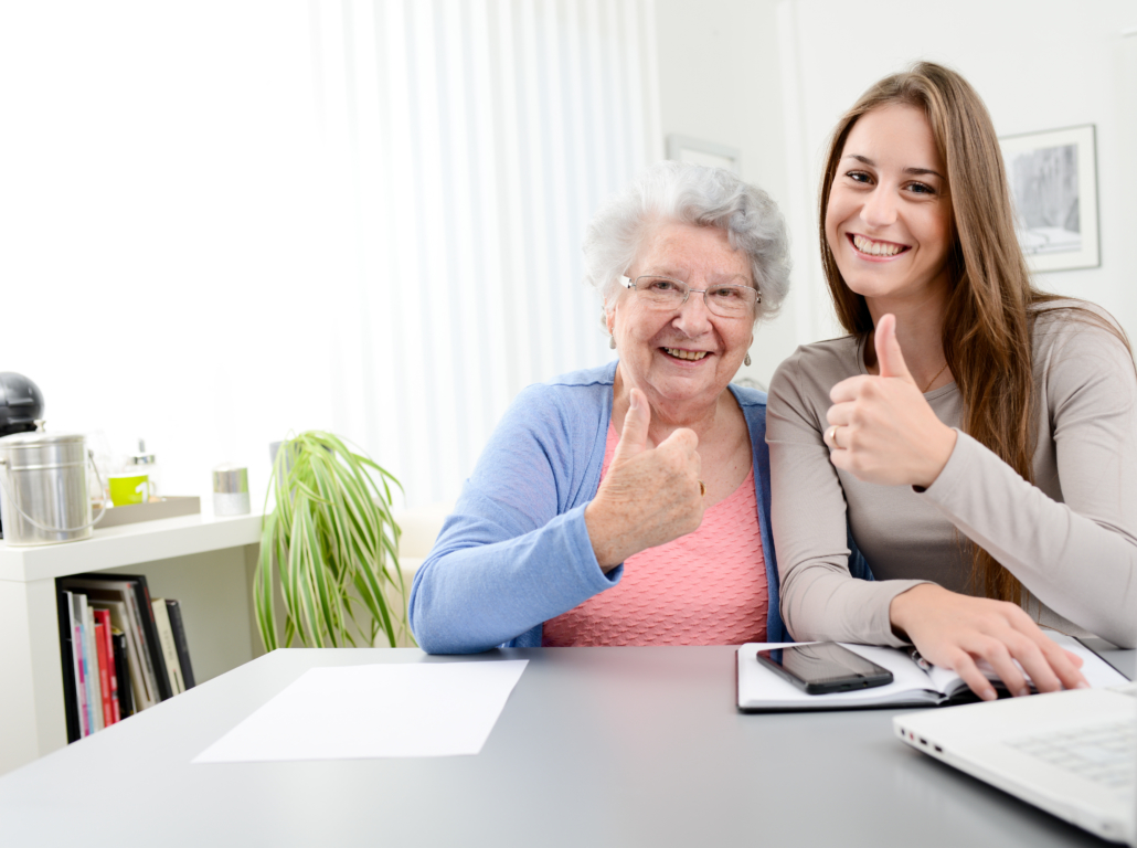 Junge Frau hilft älterer Frau beim Arbeiten mit dem Computer